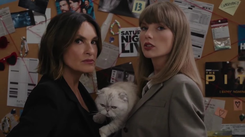 Mariska Hargitay and Taylor Swift holding the cat Olivia Benson in front of a board covered in papers, post-its, and red string.