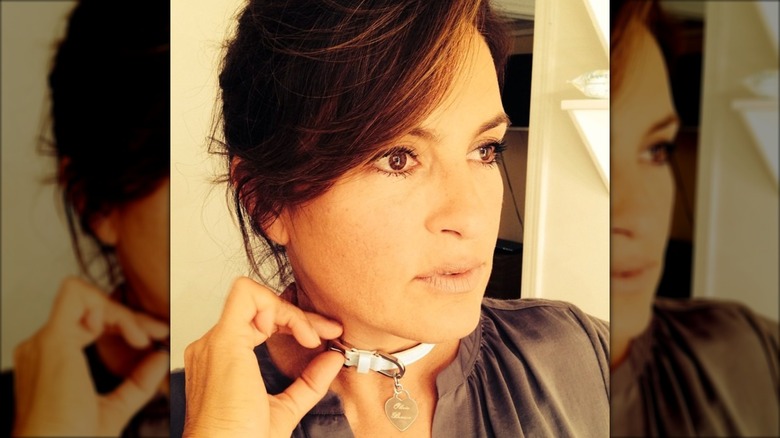 Mariska Hargitay wearing a cat collar around her neck with a tag that says Olivia Benson.