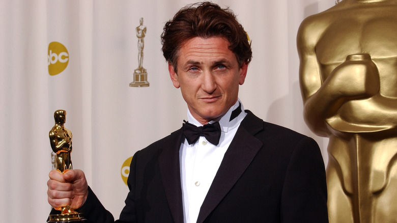 Sean Penn holding an Academy Award and posing.
