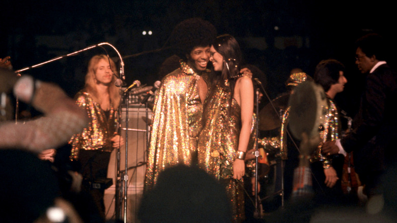 Sly Stone and Kathy Silva on stage wearing gold sparkly outfits in 1974 at Madison Square Garden