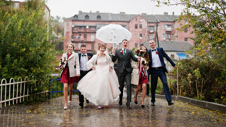 Birde and groom leading wedding party in the rain