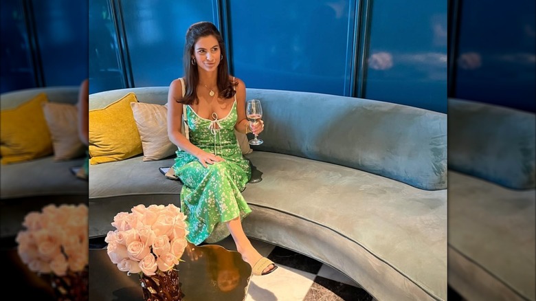 Kaitlan Collins sitting and holding a wine glass