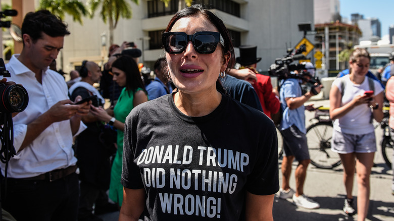 Laura Loomer yelling in sunglasses and a black pro-Trump T-shirt