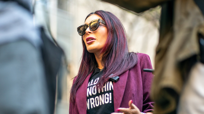 Laura Loomer with red highlights and sunglasses speaking during a protest