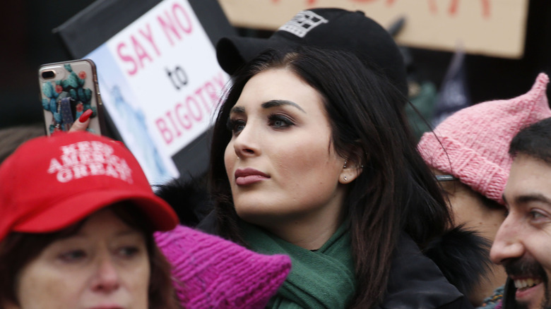 Laura Loomer filming a crowd on her phone while attending a protest