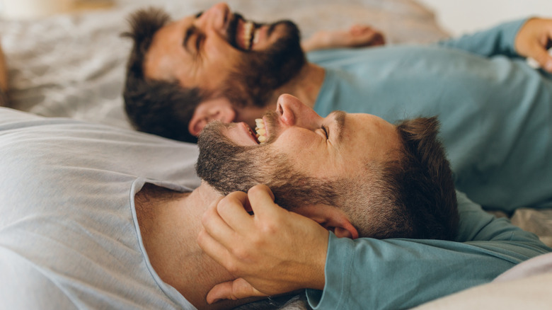 Men laughing in bed together