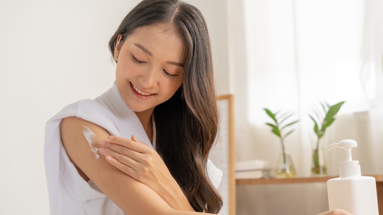 Woman applying moisturizer to her upper arm 