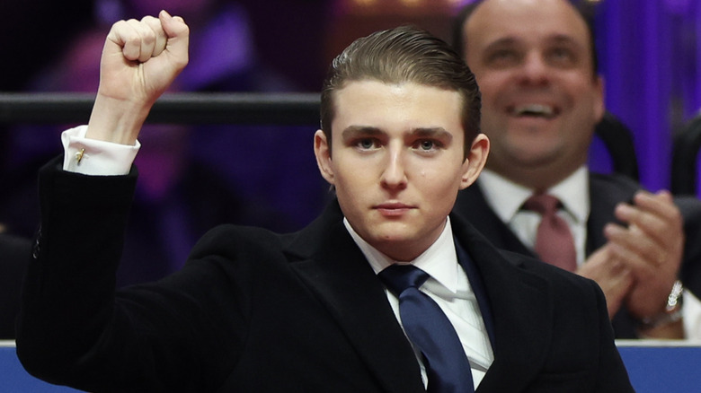 Barron Trump first pumping the air in a black suit with a navy tie