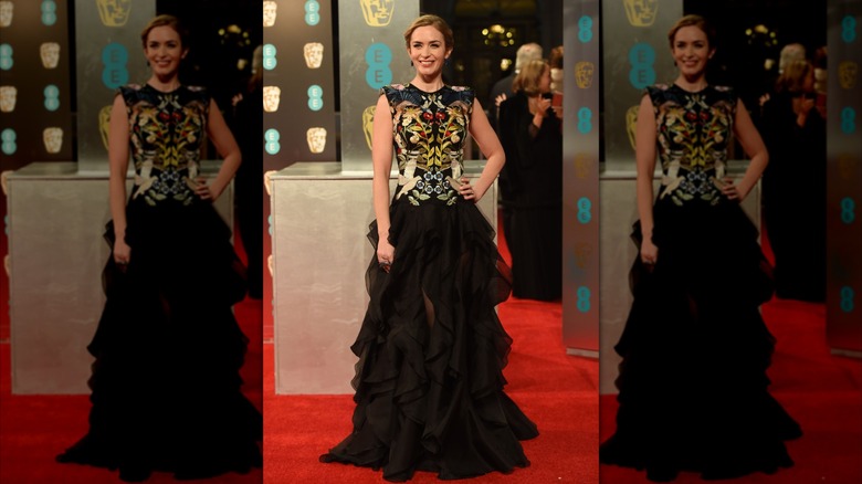 Emily Blunt smiles in a black gown with floral embroidery