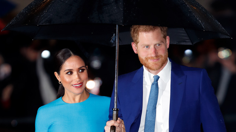 Meghan and Harry walking under umbrella