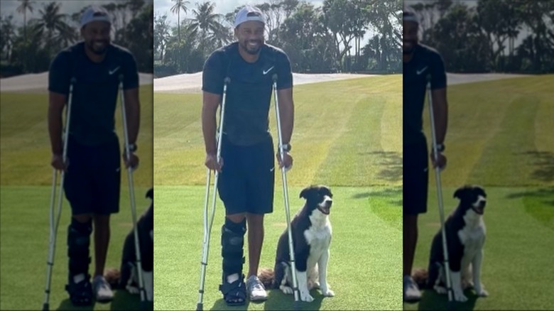 Tiger Woods using crutches, pictured with a dog on a golf course in 2021