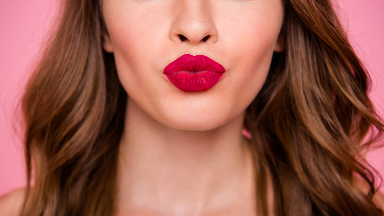 Woman wearing lipstick puckering up