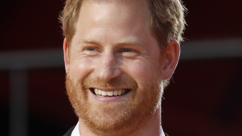 Prince Harry laughing onstage with a microphone