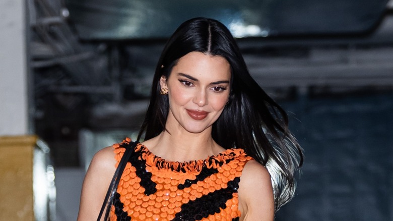 Kendall Jenner smiling and looking down while walking