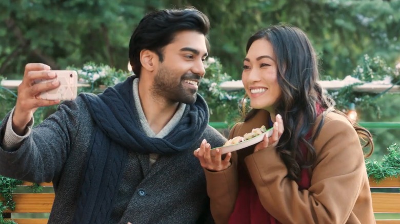 Raymond Ablack and Catherine Haena Kim taking a selfie in a scene from Boyfriends of Christmas Past (2021)