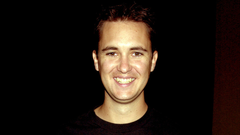 A younger Wil Wheaton smiling against a dark background