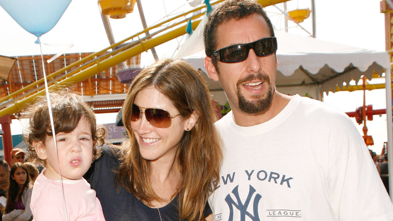 Adam, Jackie, and Sadie Sandler smiling at the Santa Monica Pier