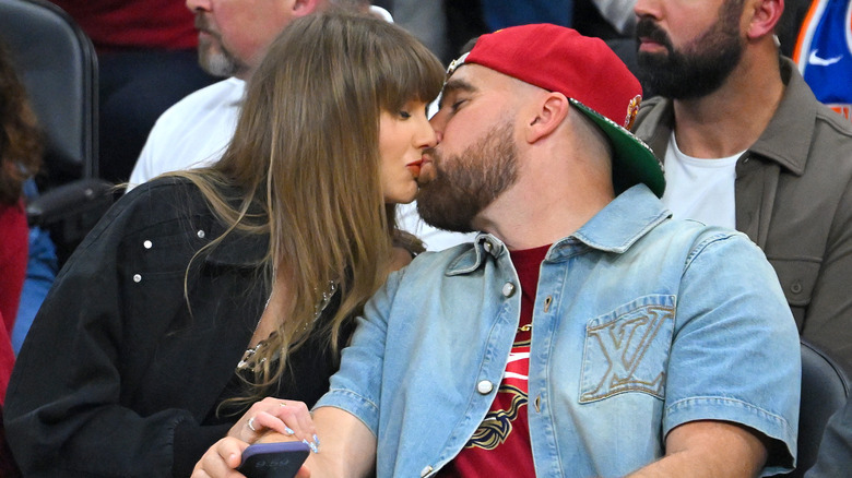 Taylor Swift and Travis Kelce kissing at a game