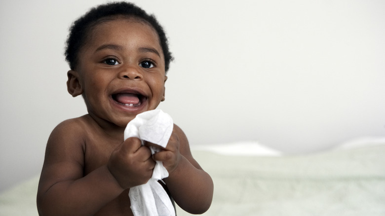 Baby holding blanket and laughing