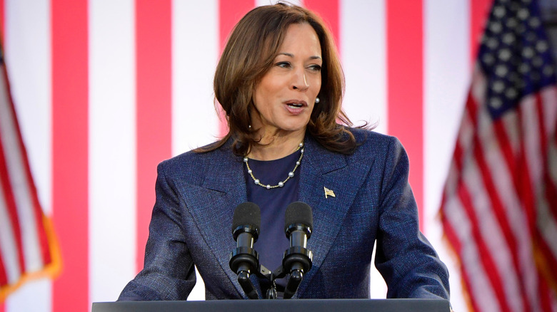 Kamala Harris standing at podium in front of American flag backdrop