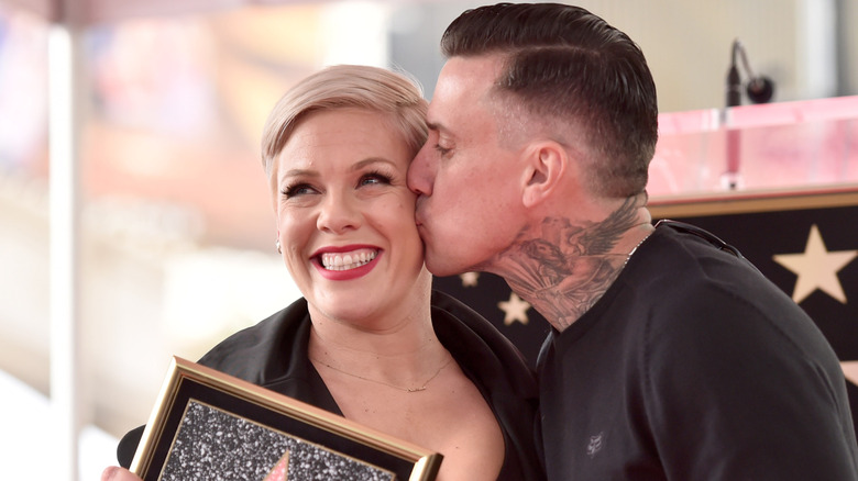 Carey Hart kissing Pink on the cheek as she smiles