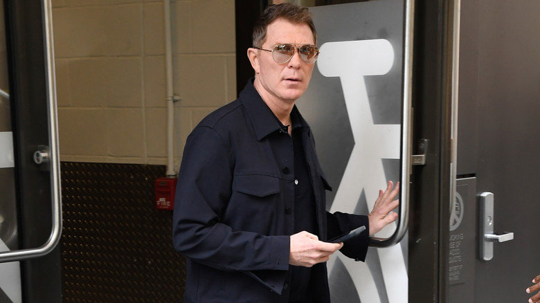 Bobby Flay exiting a building while wearing sunglasses and a black shirt