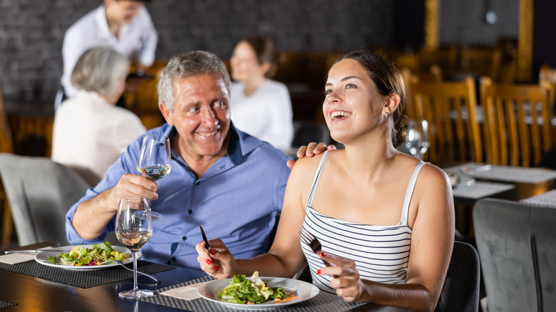 Older man and young woman laughing in restaurant