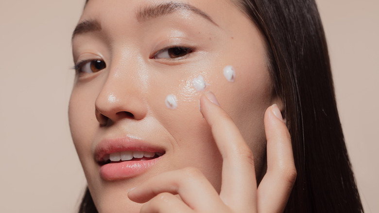 Woman applying skincare to cheeks  