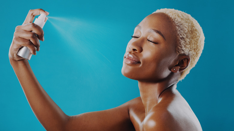 Woman applying setting spray on face