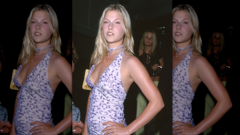 Ali Larter poses with a hand on her hip in a purple spotted halter top.