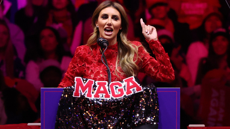 Alina Habba speaking at a Trump rally and showing off her MAGA jacket