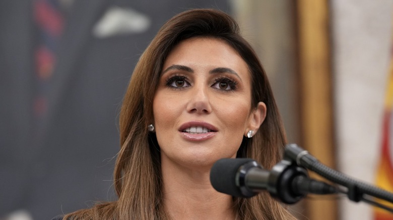 Alina Habba standing at a microphone while wearing diamond earrings