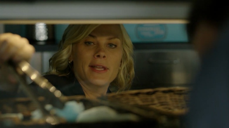 Alison Sweeney using tongs to turn baked goods in an oven