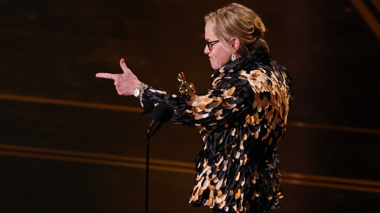 Amy Madigan doing finger guns on stage with her Oscar