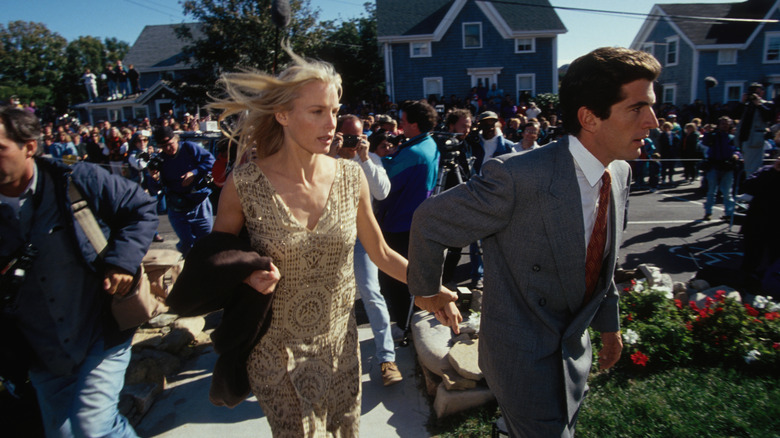 Daryl Hannah in sleeveless yellow dress holding hands with JFK Jr