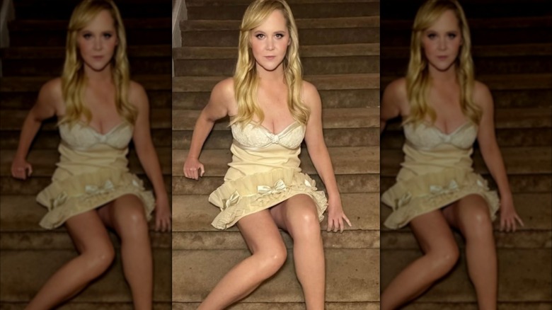 Amy Schumer in a strapless yellow dress on a brown flight of stairs