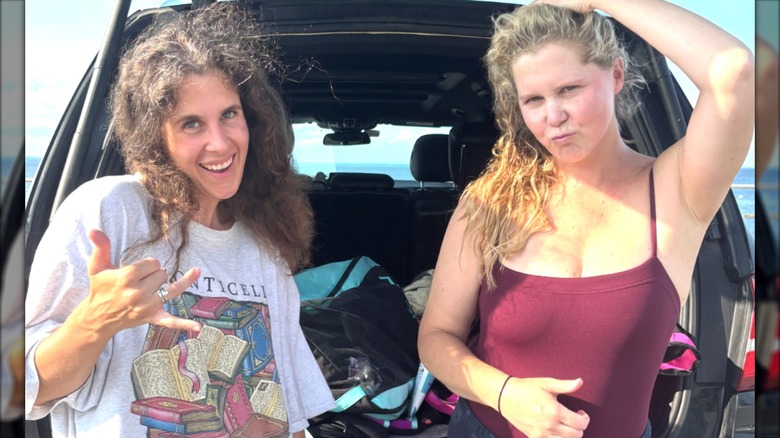 Amy Schumer and a friend posing by the trunk of a car