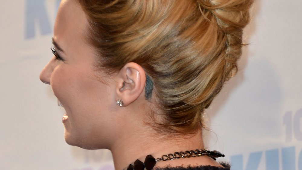 Demi Lovato looking away with her feather tattoo visible