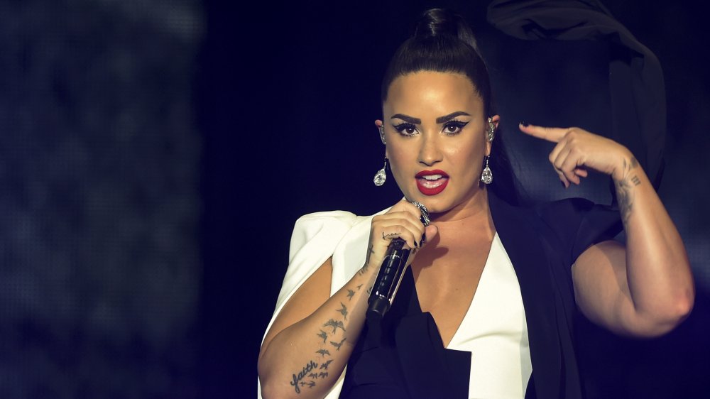 Demi Lovato performing in 2018 with her bird tattoo visible
