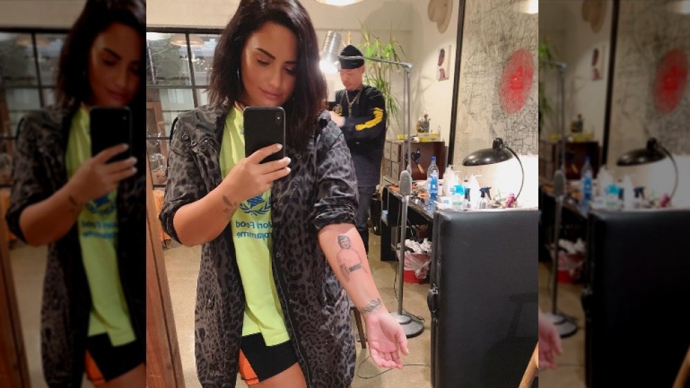 Demi Lovato tirando uma selfie com sua tatuagem de retrato