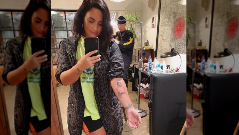 Demi Lovato taking a selfie featuring her portrait tattoo