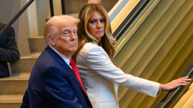 Melania Trump scowling at Donald Trump as they ascend an escalator