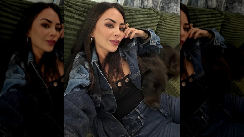 Janel Parrish sitting on a couch with her dog.