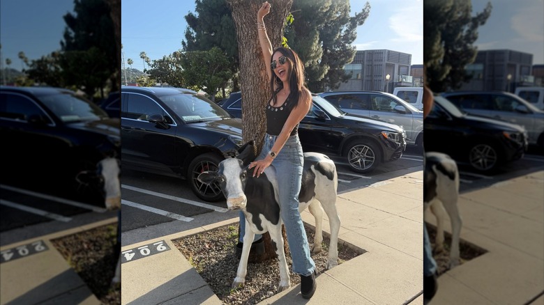 Janel Parrish pretending to ride a statue of a calf.