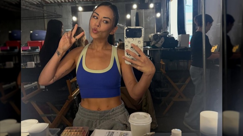 Janel Parrish making a peace sign while taking a mirror selfie.