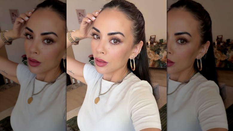 Janel Parrish wearing a white shirt and coin necklace.