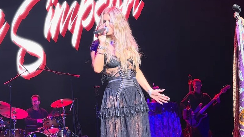 Jessica Simpson performing in a black lace dress and garter belt.