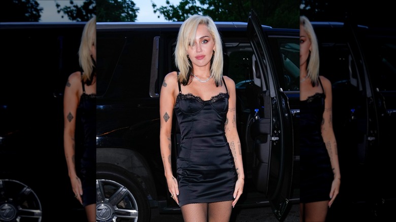 Miley Cyrus with bleach-blond hair and dark tips, stepping out of a car