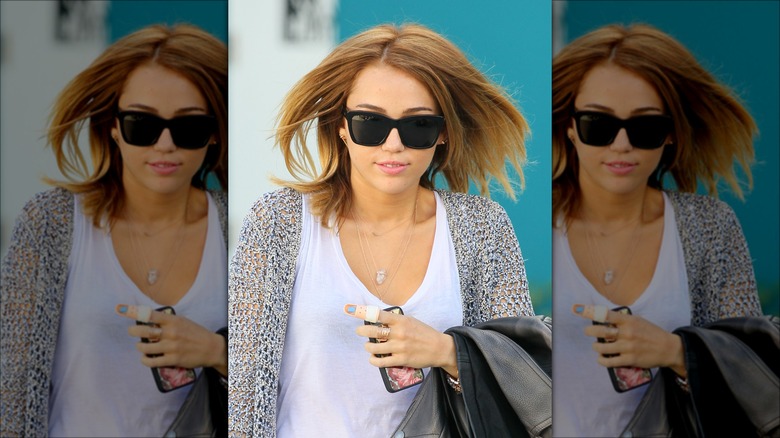 Miley Cyrus wearing sunglasses, her finger in a bandage
