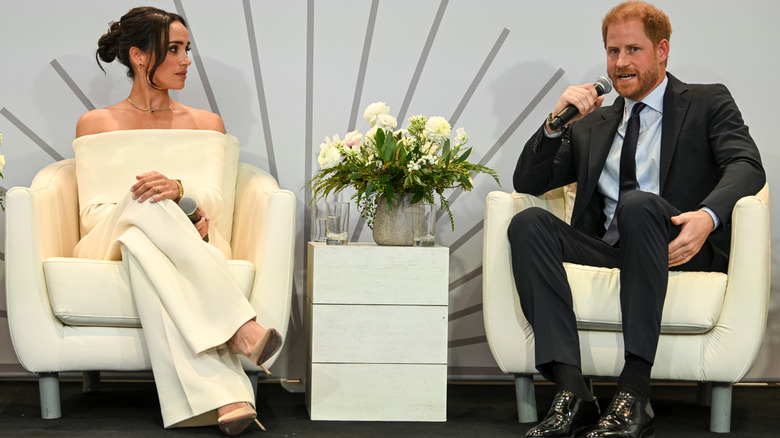 Meghan Markle and Prince Harry sitting on a stage